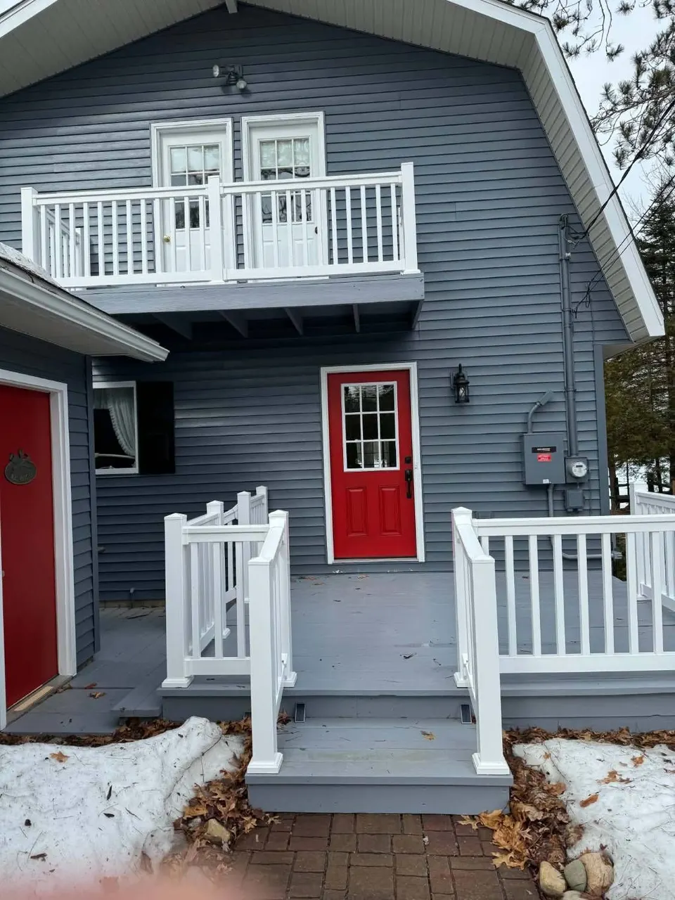 Finished entry deck and stairs with white vinyl railings leading to a red front door