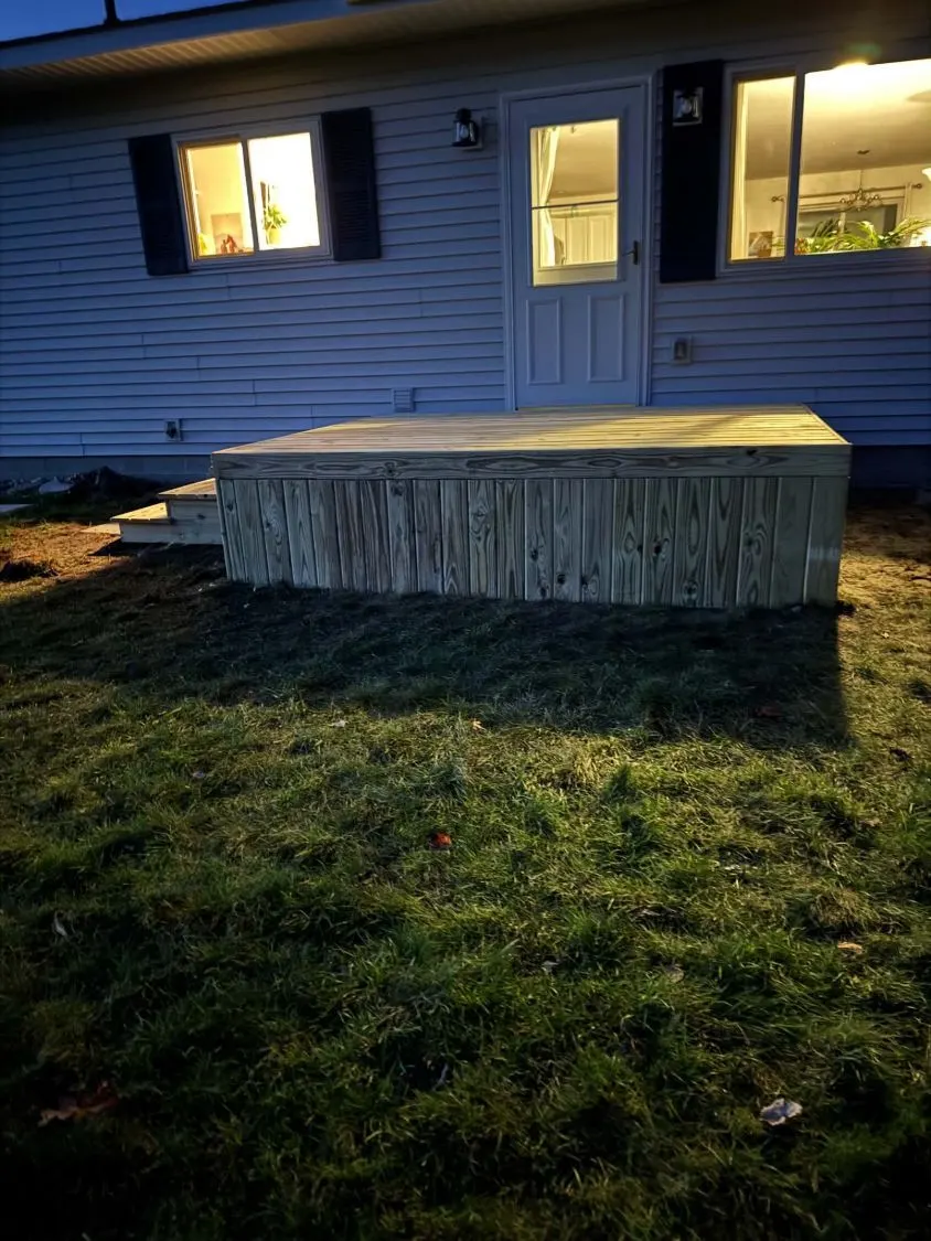 New pressure-treated back deck with vertical board skirting at dusk