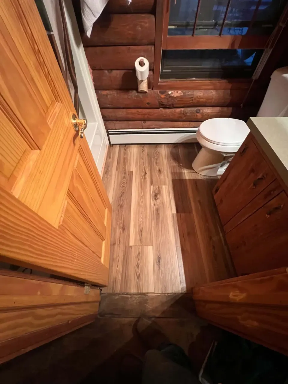 Log cabin bathroom with new wood-look vinyl plank flooring